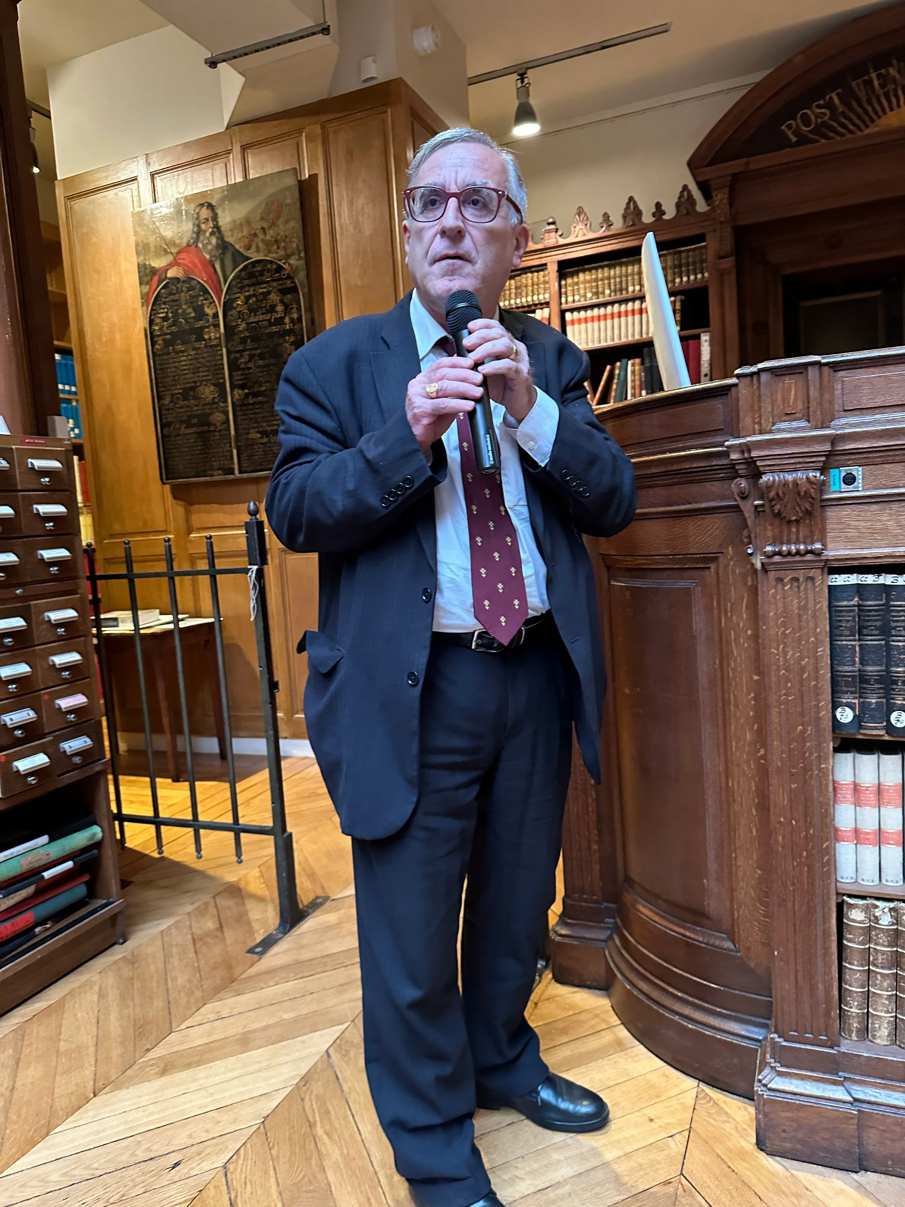 Photo de Henri Zuber tenant un micro, il est en costard.